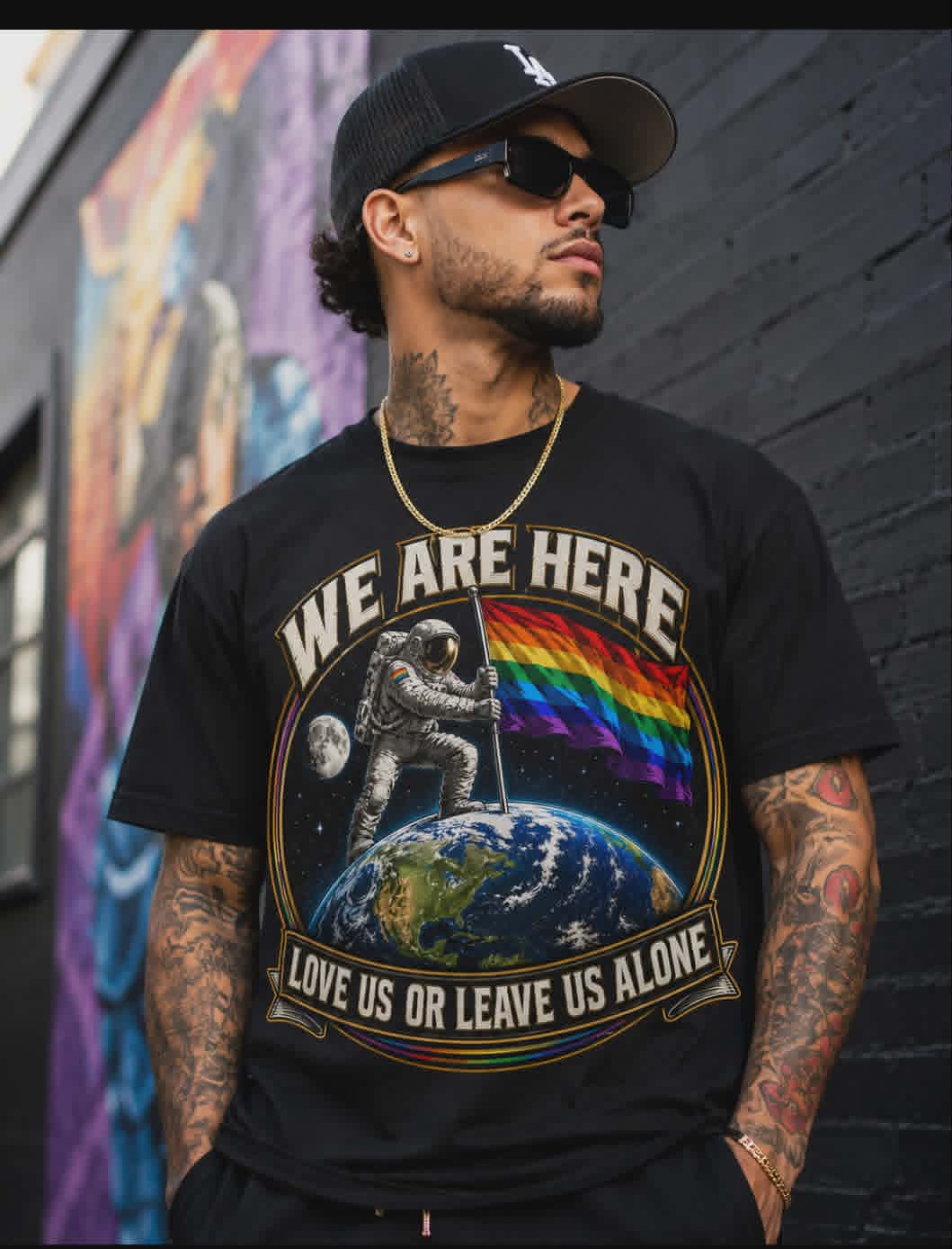 Man wearing a black t-shirt with a graphic design and text, standing in front of a colorful mural.